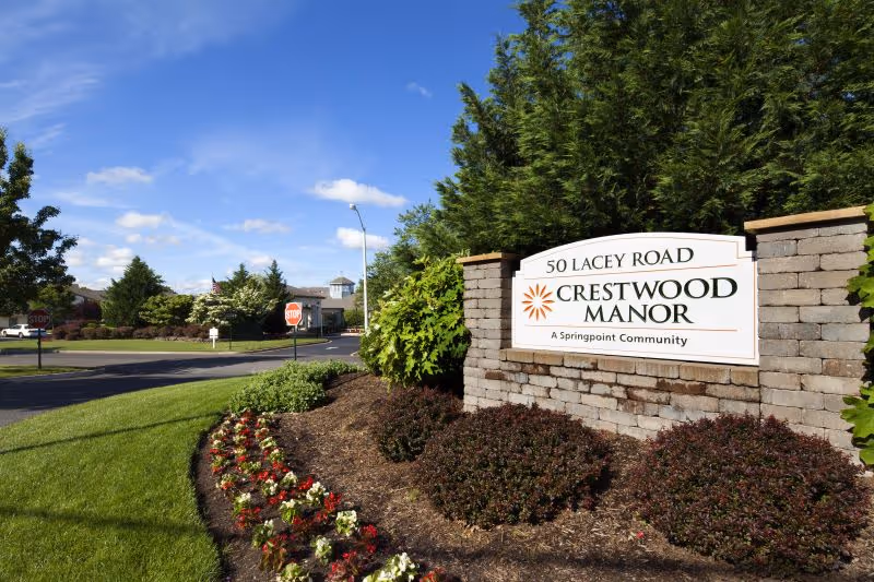 Crestwood Manor entrance sign on a stone wall with landscaped garden.