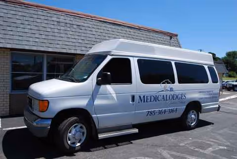 White Medicalodges van parked outside a building under a clear blue sky.