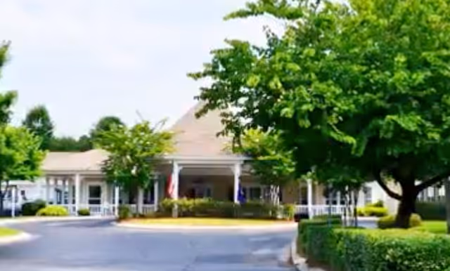 Exterior of Rock Hill Grove Senior Living entrance with trees and a curved driveway.
