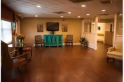 The Guest House living area with wooden floors, seating, and plants.