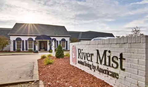 Exterior view of River Mist senior living facility with a brick sign and entrance.