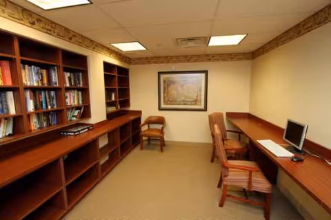 A quiet study area with bookshelves, desks, chairs, and framed wall art.
