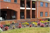 Front facade of a brick senior living building with balconies, landscaped flowerbeds and a stone sign reading "St. Francis Home".