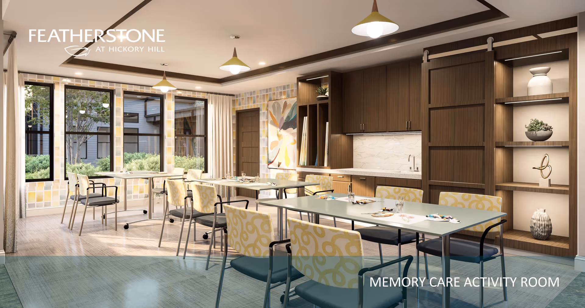 Bright memory-care activity room with multiple tables and chairs, large windows, and a kitchenette with wooden cabinets and shelves.