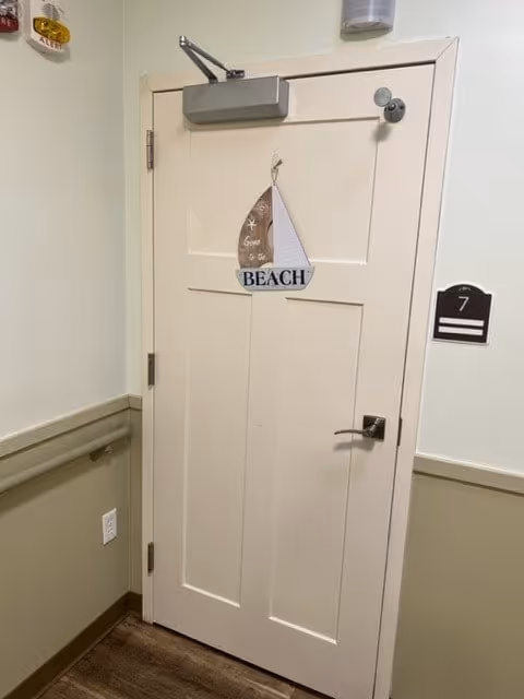 Interior hallway door with a small sailboat 'BEACH' decoration and a room number 7 plaque.