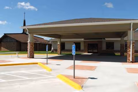 Covered entrance with brick columns and handicap parking at NewAldaya Lifescapes facility.