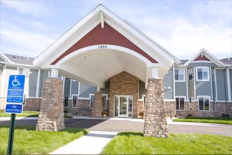 Senior living facility entrance with stone pillars and a covered porte-cochère.