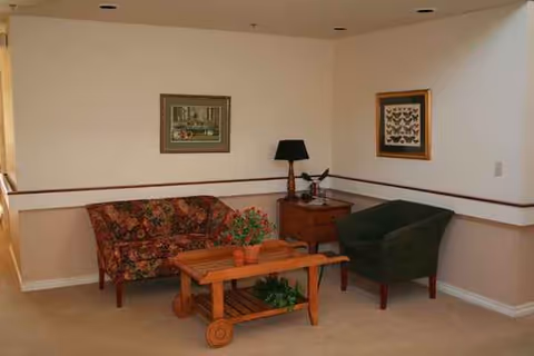 Cozy lounge area with floral sofa, green chair, lamp, and coffee table.