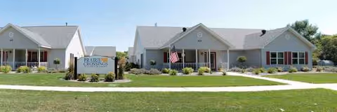 Two single-story memory care buildings with manicured landscaping and entrance signs.
