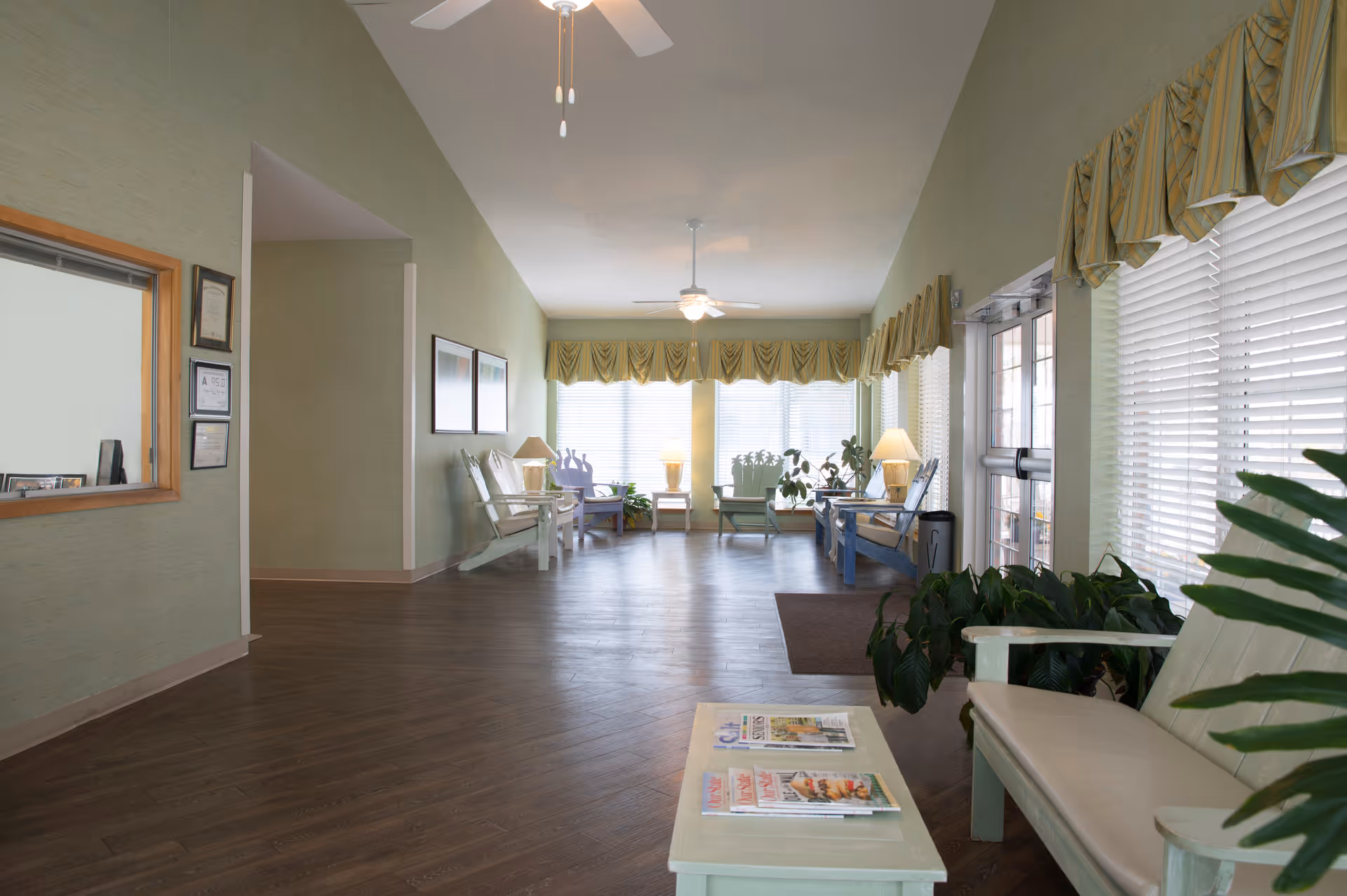 Reception/lobby area with seating, plants, and large windows in a senior living facility.
