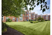 Brick senior living building with well-kept lawn and trees