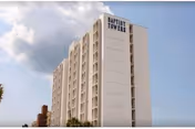 White multi-story apartment building with balconies and a sign reading "Baptist Towers" against a partly cloudy sky.