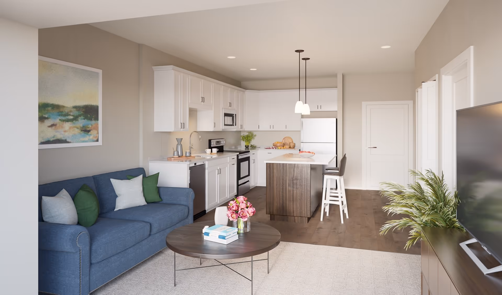 Open-plan living room and kitchen with a blue sofa, round coffee table, island with stools, and white cabinets.
