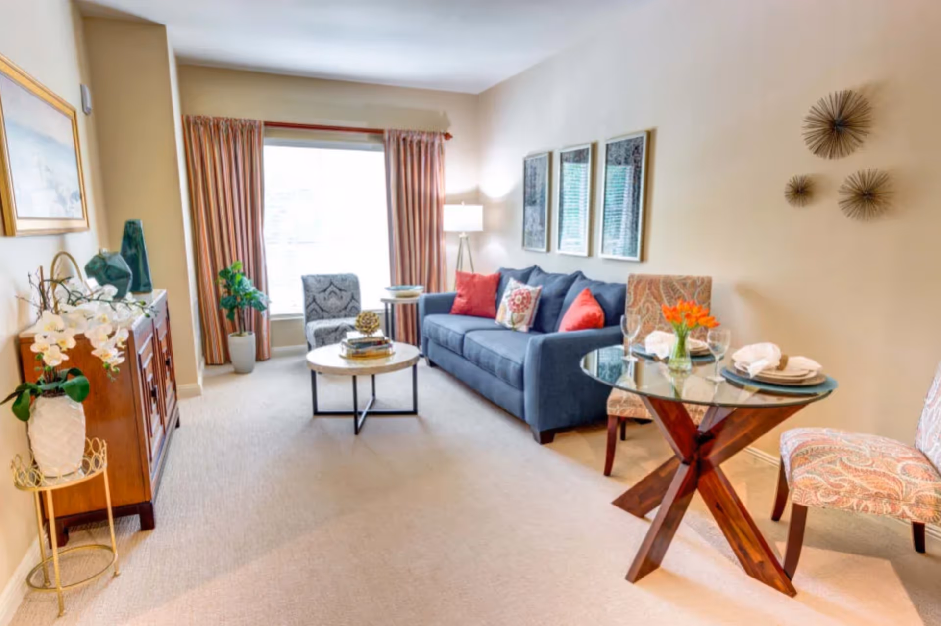 Bright living room in The Meridian at Boca Raton with blue sofa and glass dining table.