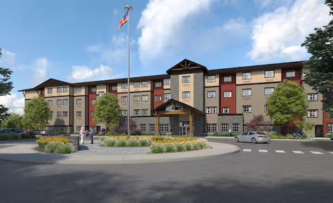 Four-story senior living building with a covered entrance, circular driveway, flagpole, landscaping, and parked cars under a blue sky.