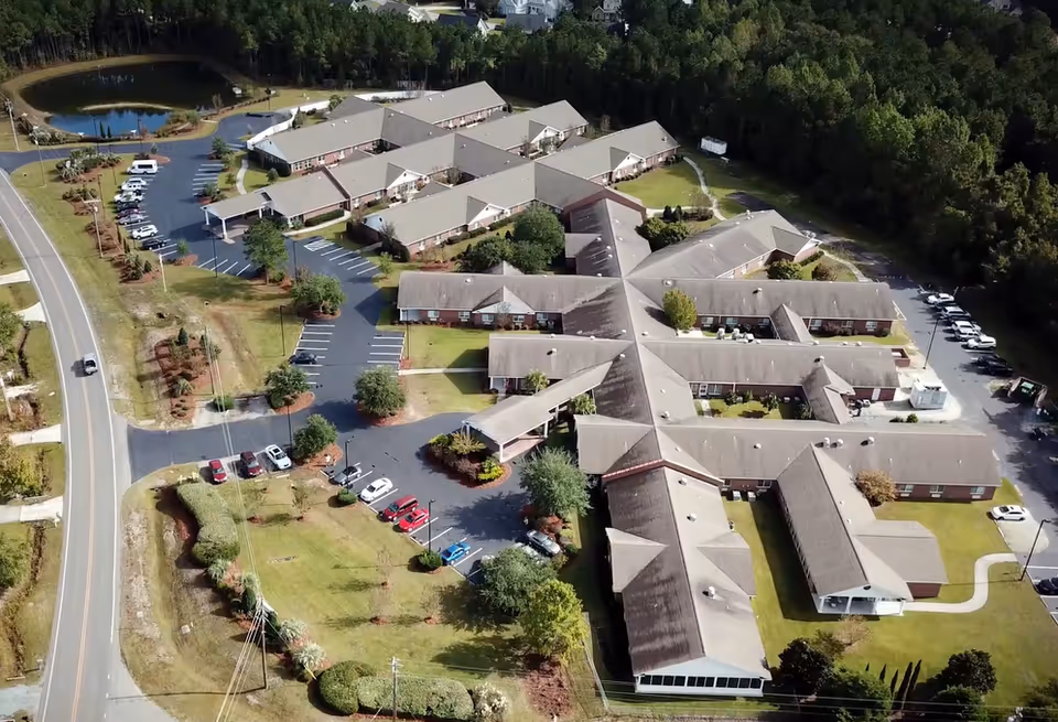 Aerial view of the Woodbury Wellness Center campus showing low-rise connected buildings, parking lots, lawns, and surrounding trees.