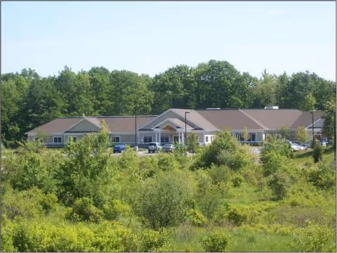 Exterior view of a single-story Watson Fields senior living facility amid trees.