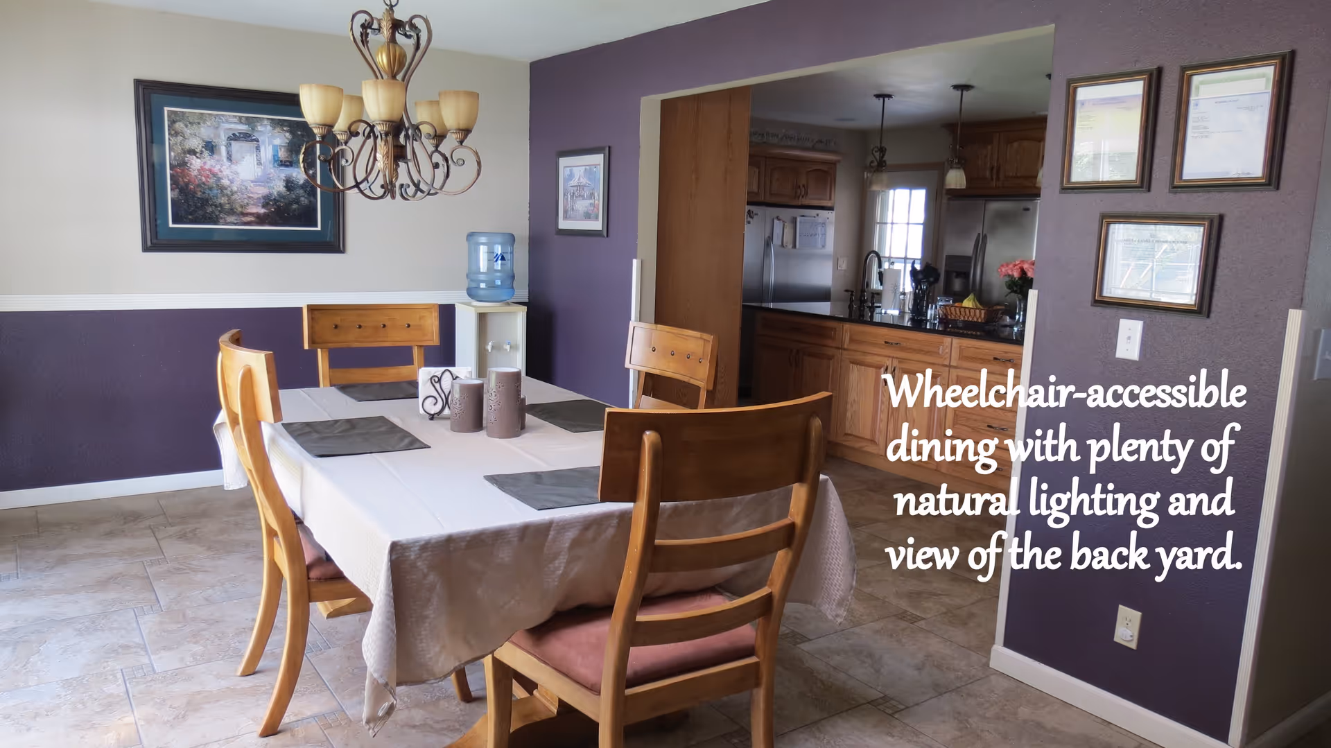 Dining room with a table and wooden chairs under a chandelier and an open pass-through to the kitchen.