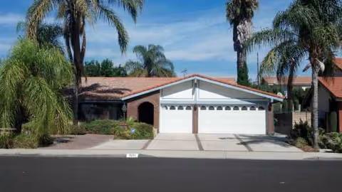 Front view of Genesis Manor IV exterior with a two-car garage and palm trees.