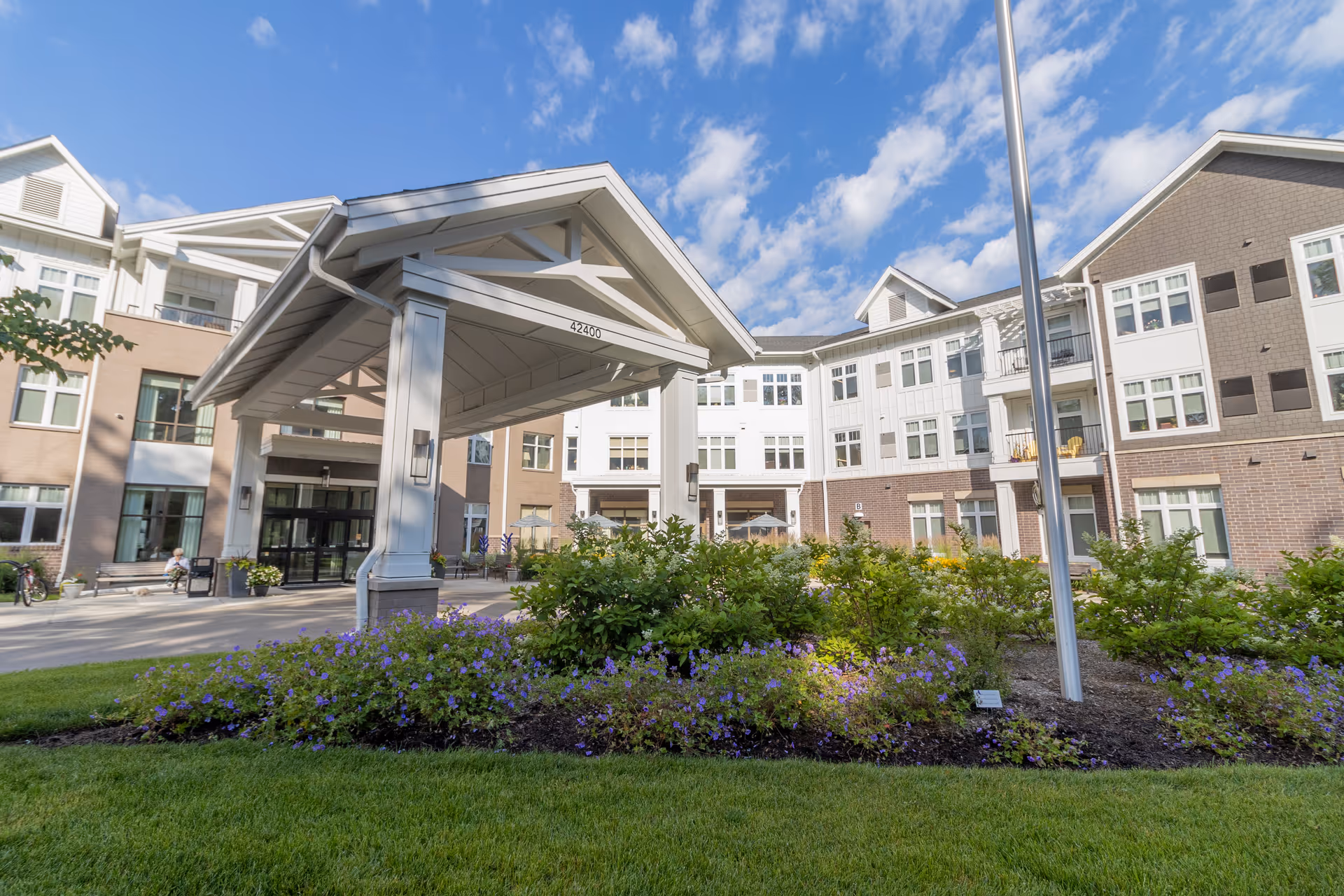 Front view of StoryPoint Novi senior living campus with covered entrance and landscaped grounds.
