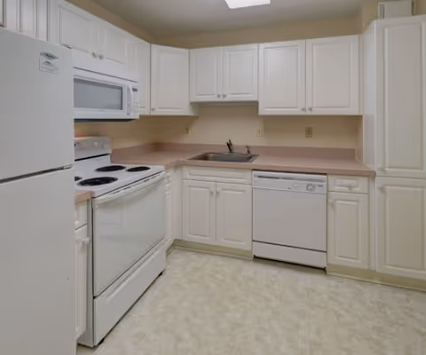 Compact all-white kitchen with refrigerator, stove, microwave, dishwasher, sink, and cabinetry.