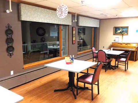 Indoor dining room with tables, red chairs, and a piano in the corner.