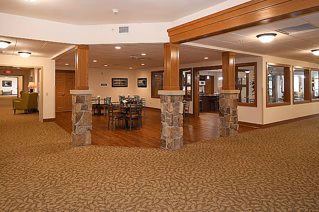 Open interior common area featuring wooden columns with stone bases and a small dining area with tables and chairs.