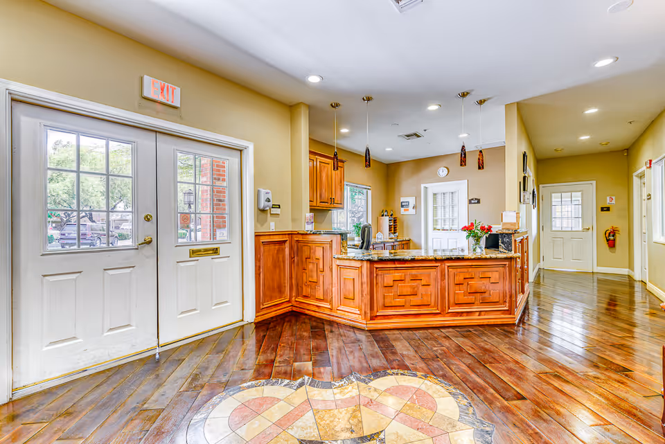 Reception lobby with a wooden check-in desk, double entry doors, and polished hardwood floors.