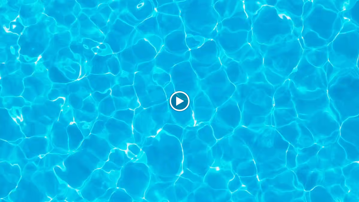 Clear blue water in a swimming pool with sunlight reflecting on the surface.