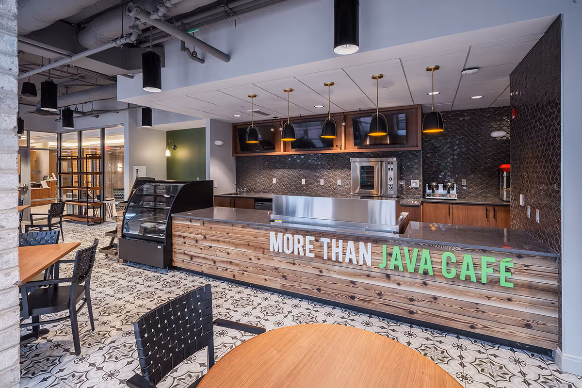 Modern interior café and seating area with a wood-front counter labeled 'MORE THAN JAVA CAFÉ'.