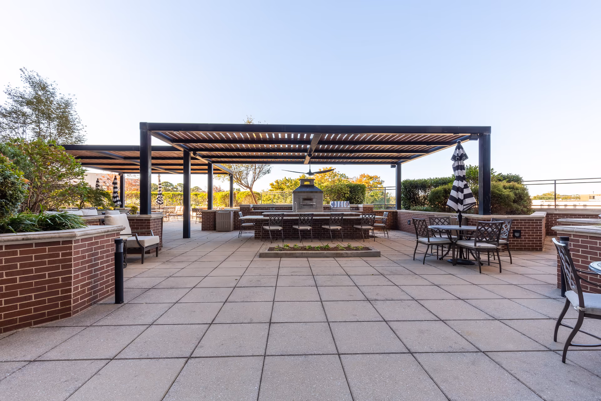 Rooftop outdoor patio with pergola-covered seating, tables, and a central fireplace.