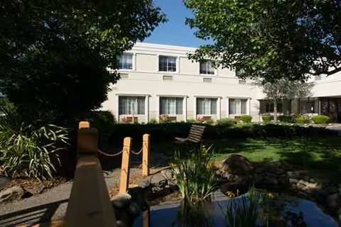 AristaCare at Whiting exterior building with a landscaped courtyard and small pond.