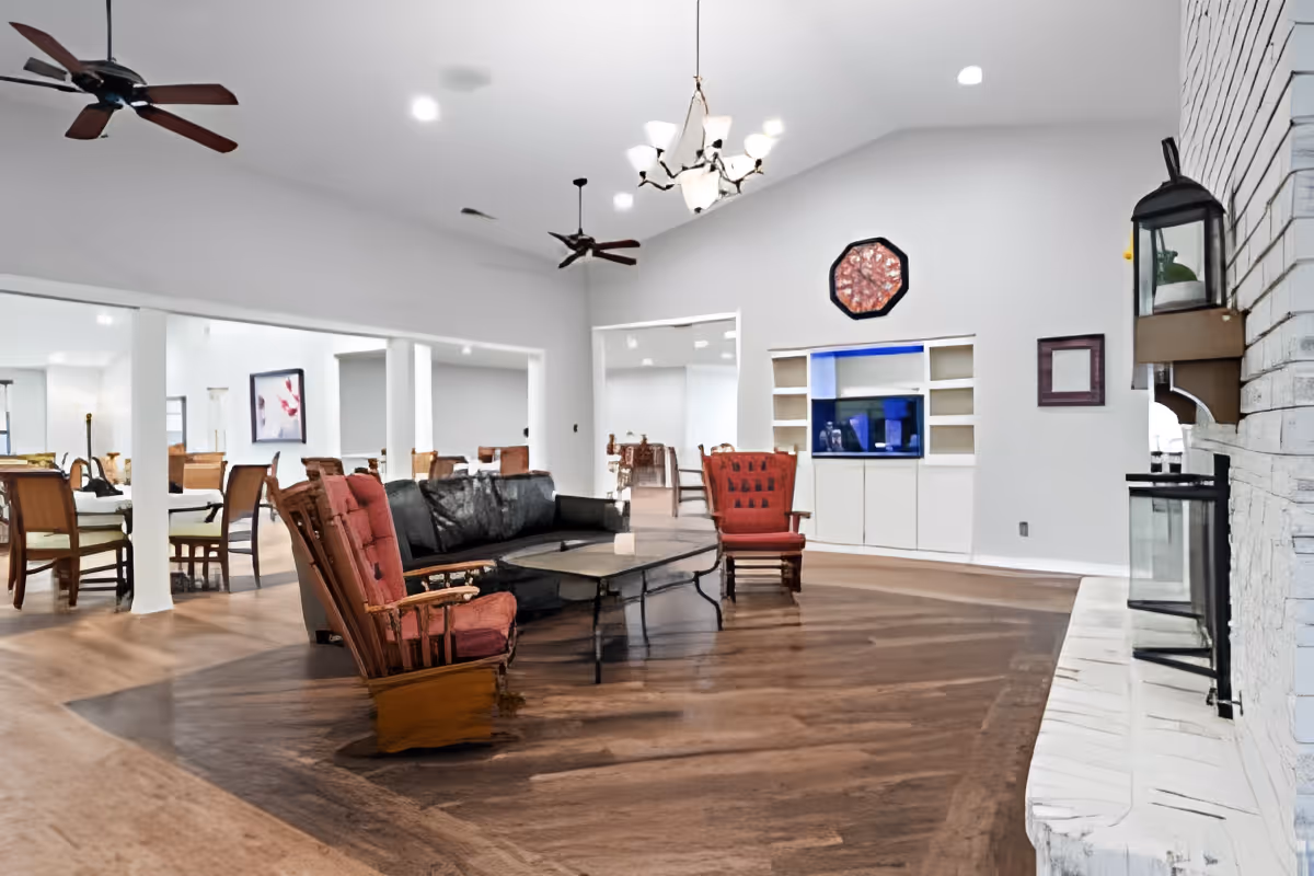 Spacious communal living room with vaulted ceiling, seating area and coffee table, fireplace on the right, and built-in TV shelving.