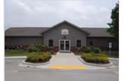 Front view of Wesley Village Retirement Center entrance with landscaping and parking.