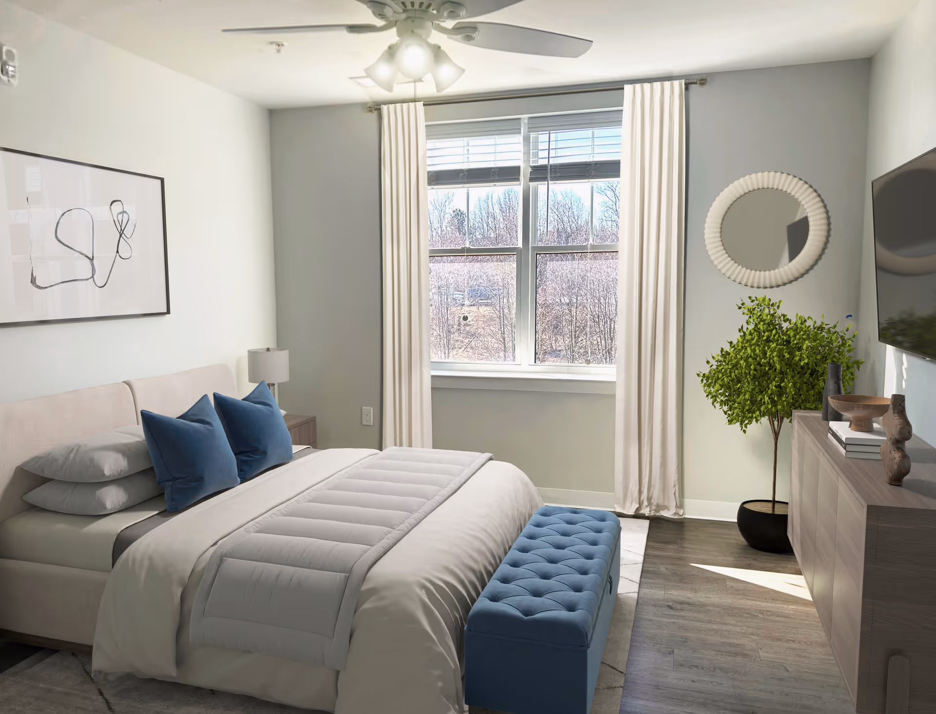 Sunlit modern bedroom with a made bed featuring blue pillows and a tufted bench, a window with curtains, dresser with TV, and a potted plant.