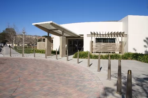 Modern white senior care center exterior with covered entrance and curved brick walkway.