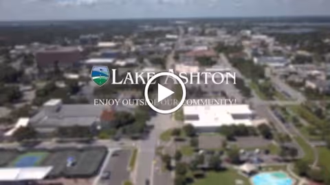 Aerial view of a suburban community and pool with the "Lake Ashton" logo overlaid.