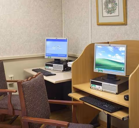 Two computer workstations with monitors and a wooden divider in a small office area.
