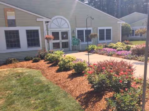 Front entrance of Peregrine's Landing at Tewksbury with pathways and colorful flowerbeds.
