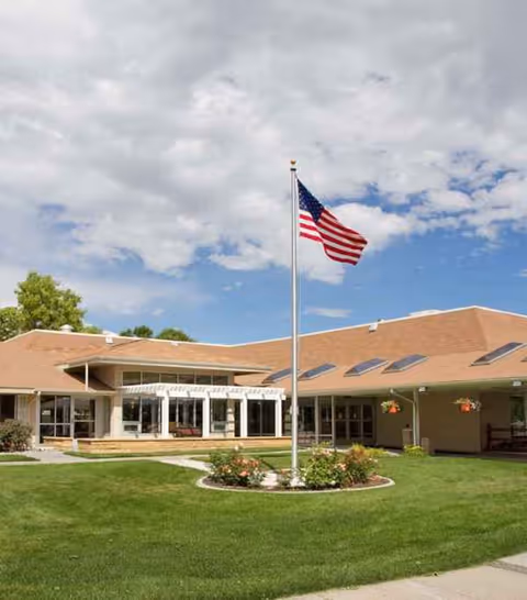 Front exterior of Yellowstone River Nursing and Rehabilitation with flagpole and manicured lawn.