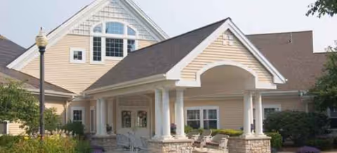 Exterior view of Brookdale East Niskayuna entrance with covered porch and beige siding.