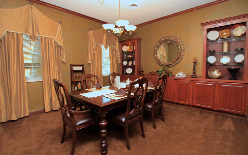 Formal dining room with a wooden table and chairs, chandelier, and built-in cabinets displaying plates.