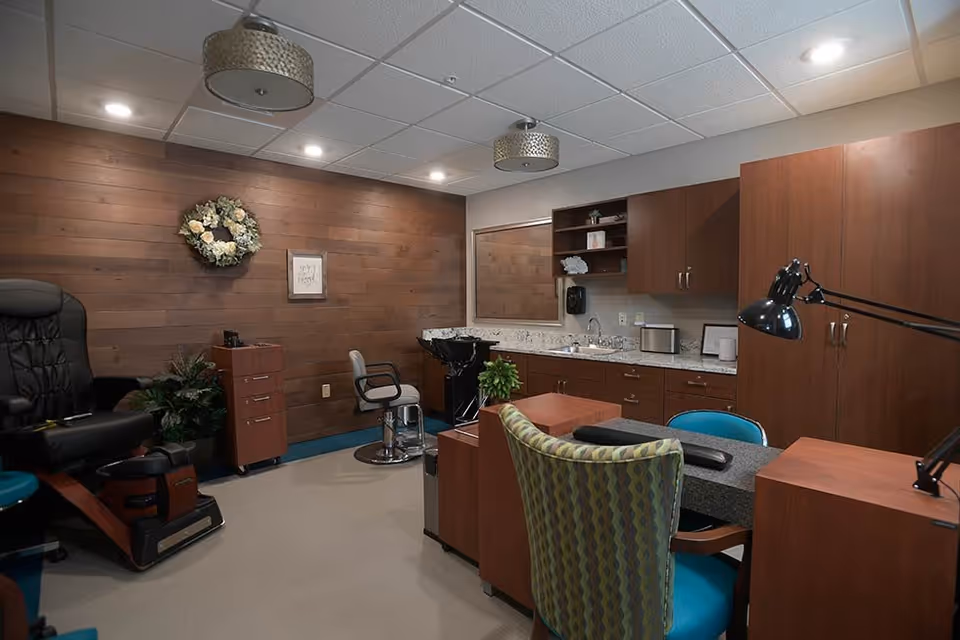 Salon-style interior with manicure stations, a pedicure chair, wood-paneled wall and cabinetry.