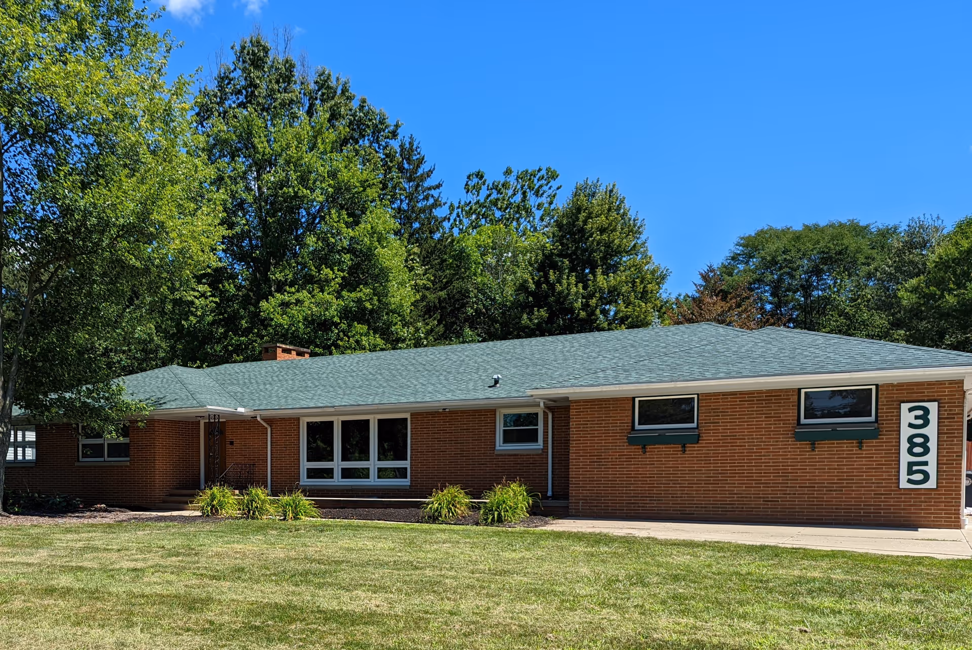 A single-story brick senior living facility set among trees and a manicured lawn.