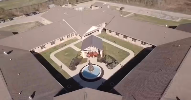Aerial view of a courtyard with a central fountain and gazebo surrounded by single-story senior living buildings and walkways.