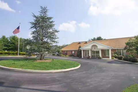 Exterior view of Hickory House Nursing Home with circular driveway and American flag.