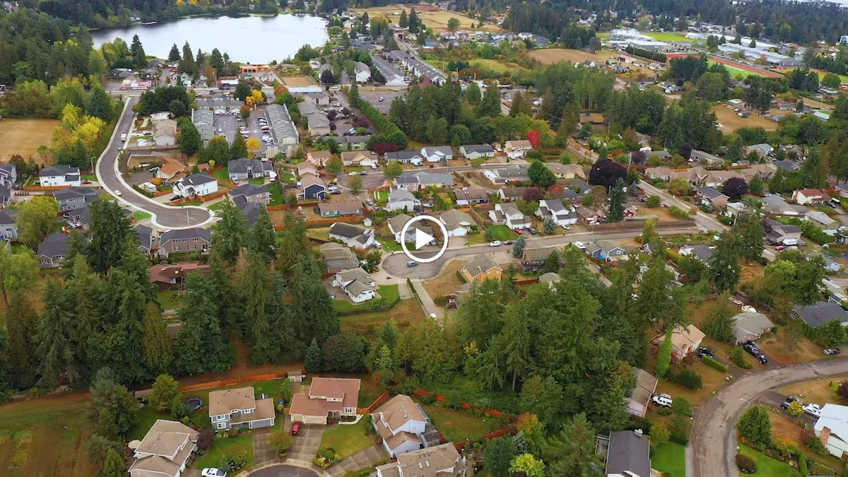 Aerial view of a residential neighborhood with houses, trees, and a nearby lake.