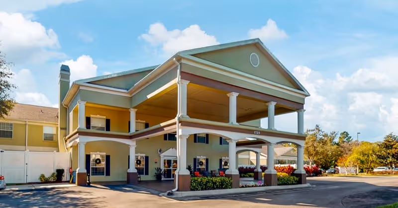Front entrance of the Madison at Oviedo building featuring a two-story covered porte-cochere with columns and landscaping.