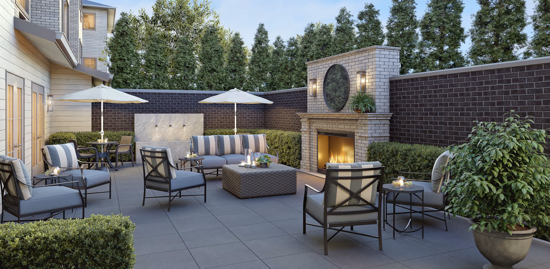 Outdoor courtyard patio with cushioned seating, umbrellas, a fireplace, and potted greenery.
