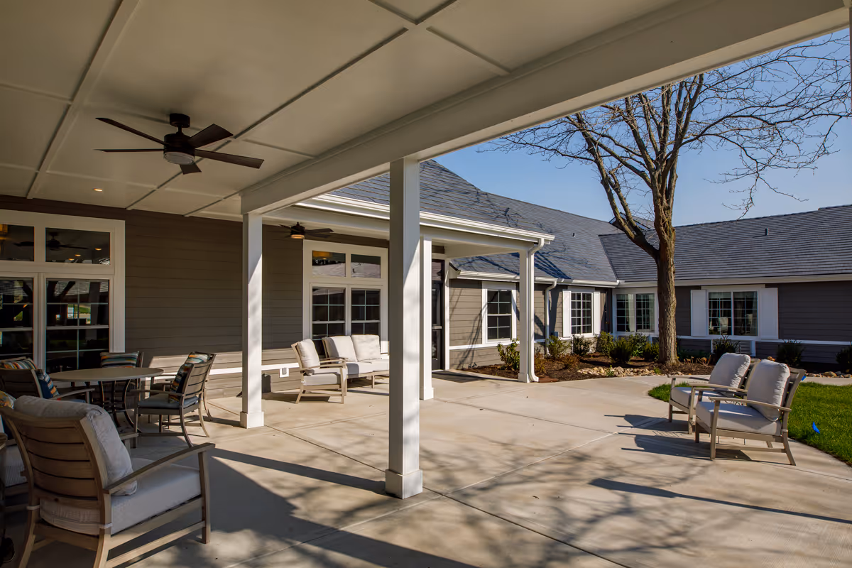 Covered outdoor patio and courtyard with seating, ceiling fans, and surrounding single-story building.